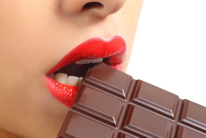 Beautiful woman red lips eating chocolate isolated on a white background